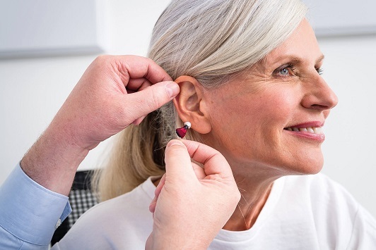 Seniorin bekommt ein modernes Hörgerät angepasst und lächelt zufrieden bei der Beratung.